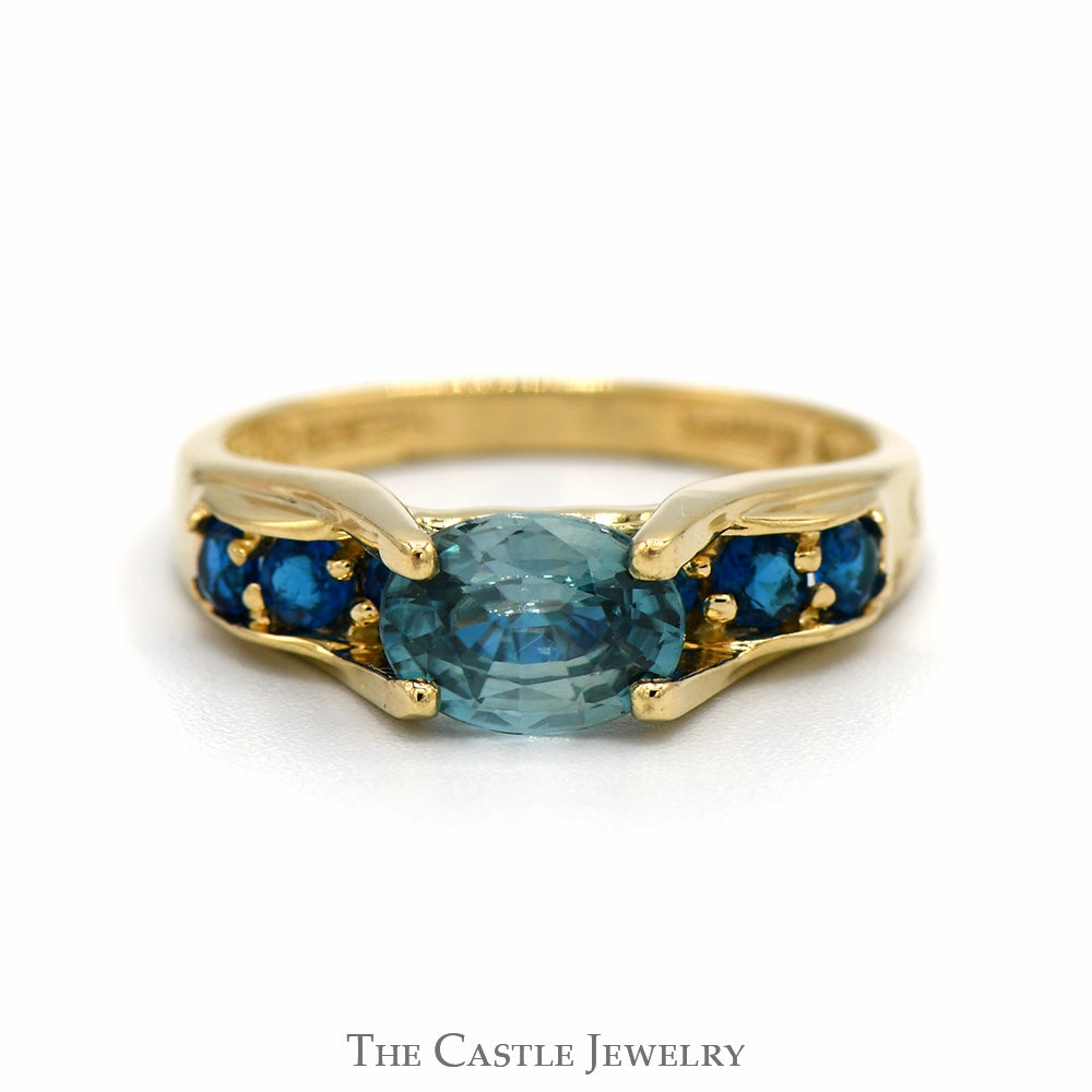 Superior Object Smooth Finish Oval Blue Zircon Ring with Blue Topaz Sides in 14k Yellow Gold Bridge Designed Mounting