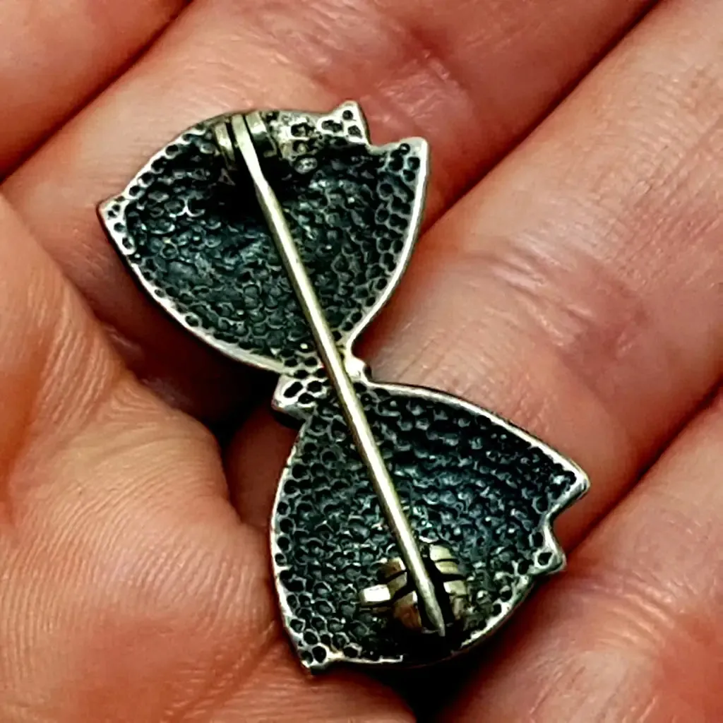Vintage silver brooch in the shape of a bow in engraved silver. Circa 1960s. Jewelry.